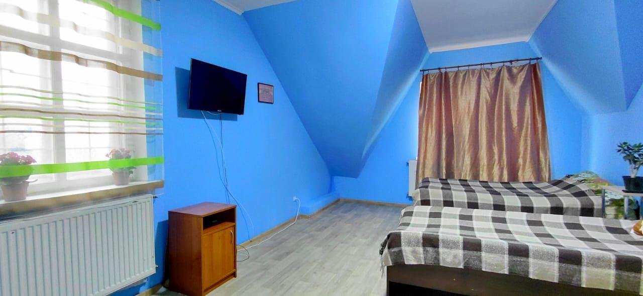 Синя кімната з двома ліжками та телевізором на стіні у центрі Рестарт+